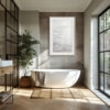 A modern bathroom features a white freestanding bath with a towel, a potted plant, sunlit large windows, and a 'Dune' print framed on the grey tiled wall.