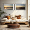 A cosy living room radiates serenity with a white cushioned sofa, brown and white cushions, a round woven ottoman, a potted plant, and sunlight streaming onto the sofa beneath two 'Serenity' Diptych Prints of abstract seaside scenes.