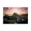‘Van Dyk’s Bay’ (H) Print captures a rocky coastal landscape at sunset, where dramatic clouds and sun rays illuminate jagged rocks and lush green vegetation by the sea.