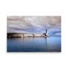 The 'Pier of Bastia' Print features the landmark’s green-topped lighthouse stretching into tranquil blue water beneath a striking, cloud-filled sky.