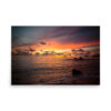 Bring home the beauty of a vibrant sunset with the 'Island Horizon' Print, featuring colourful clouds, gentle waves on a sandy shore, rocky foreground, and an island silhouette on the distant horizon.